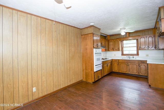 kitchen featuring a textured ceiling, dark hardwood / wood-style floors, white oven, sink, and ceiling fan