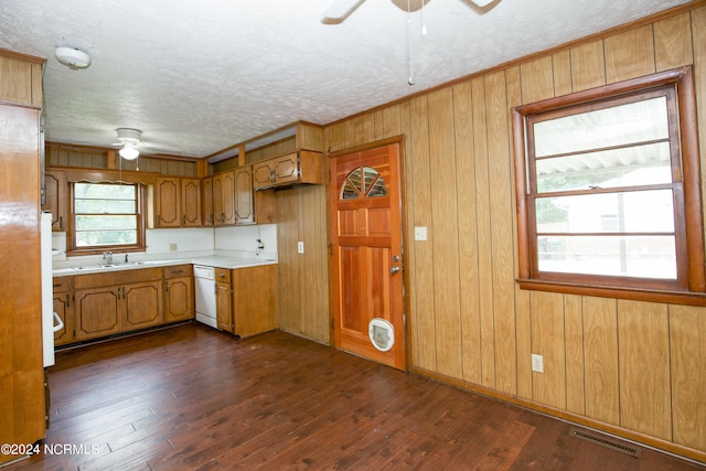 kitchen featuring white dishwasher, wooden walls, dark hardwood / wood-style flooring, ceiling fan, and a textured ceiling