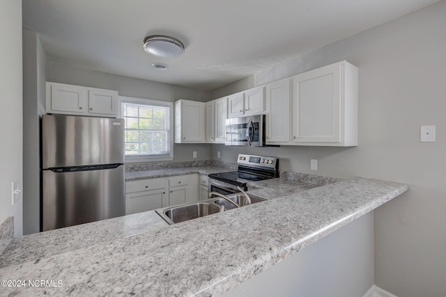 kitchen with kitchen peninsula, stainless steel appliances, white cabinetry, and sink