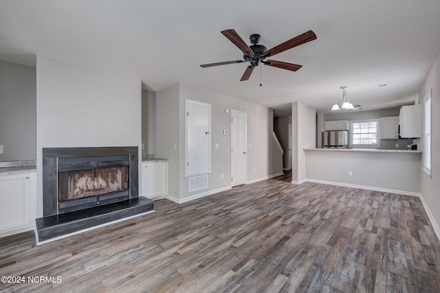 unfurnished living room featuring ceiling fan with notable chandelier and dark hardwood / wood-style floors