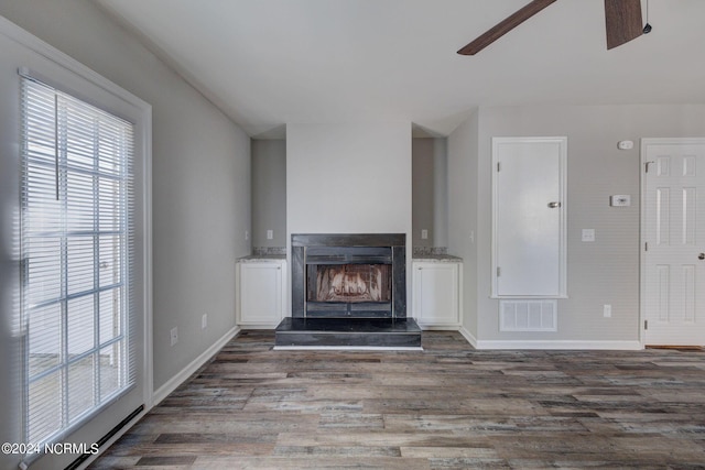 unfurnished living room with a wood stove, ceiling fan, and dark hardwood / wood-style flooring