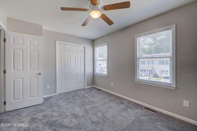 unfurnished bedroom with multiple windows, ceiling fan, a closet, and carpet floors