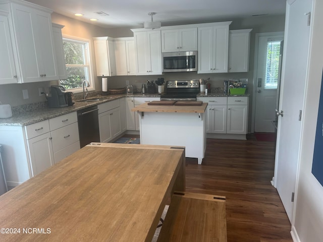 kitchen with a center island, dark hardwood / wood-style floors, sink, white cabinets, and appliances with stainless steel finishes