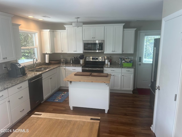 kitchen featuring dark hardwood / wood-style floors, sink, white cabinets, a kitchen island, and stainless steel appliances