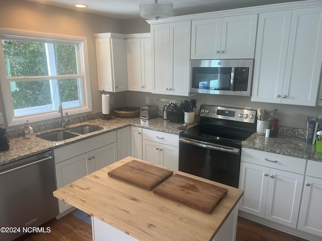 kitchen with light stone countertops, stainless steel appliances, sink, and white cabinetry