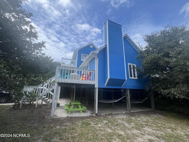 rear view of property featuring stairs and a wooden deck