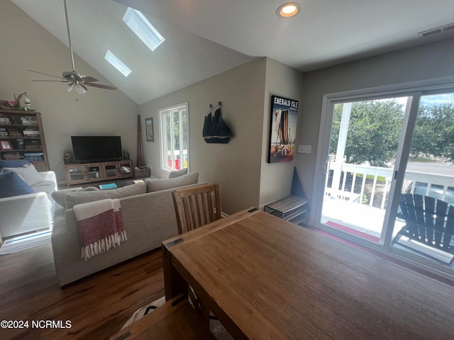 dining area with vaulted ceiling with skylight, dark hardwood / wood-style floors, and ceiling fan