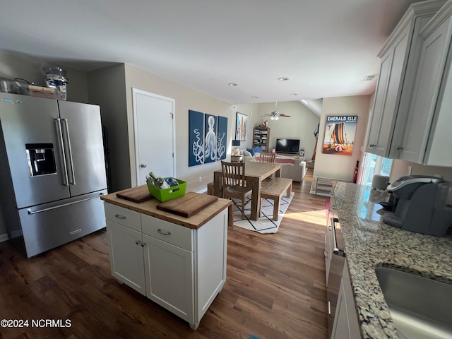 kitchen with dark hardwood / wood-style flooring, white cabinets, ceiling fan, and stainless steel fridge