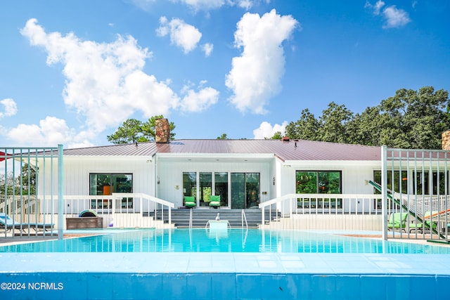 back of property with a patio area, a chimney, a pool, and metal roof