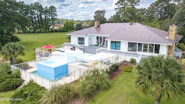 back of property featuring a fenced in pool, a yard, a chimney, metal roof, and a fenced backyard