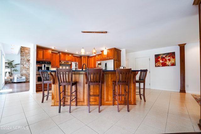 kitchen featuring appliances with stainless steel finishes, dark countertops, light tile patterned flooring, and brown cabinets