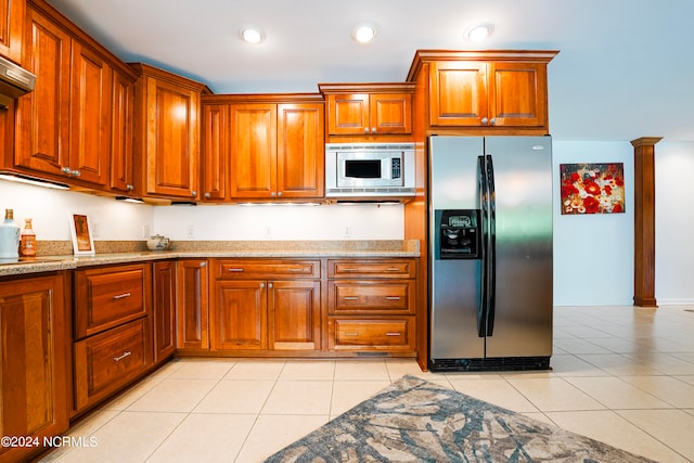 kitchen with light tile patterned floors, brown cabinetry, appliances with stainless steel finishes, light stone countertops, and recessed lighting