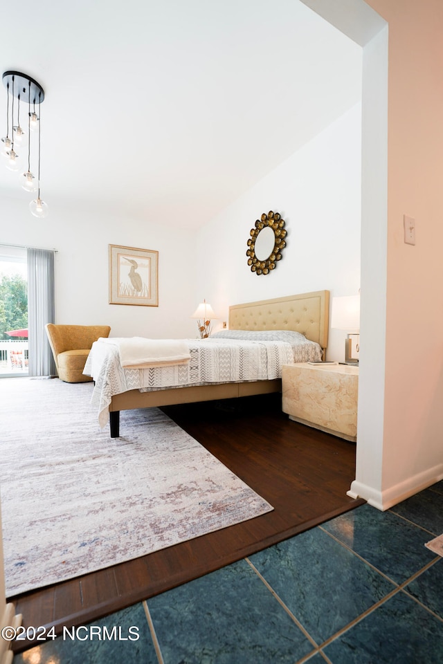 bedroom with vaulted ceiling, baseboards, and wood finished floors