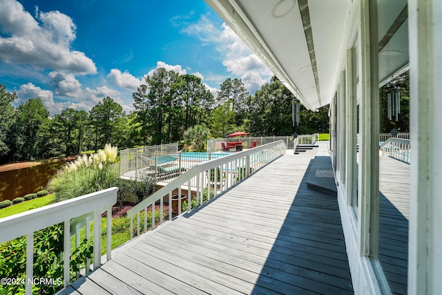 wooden terrace with a community pool and fence