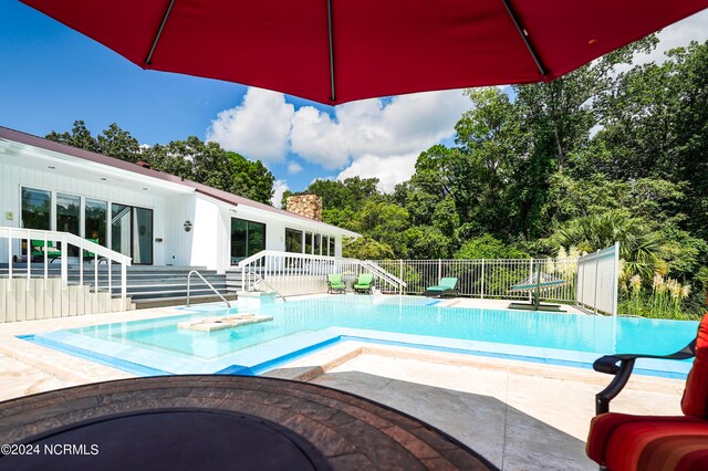 view of swimming pool featuring a hot tub, fence, a fenced in pool, and a patio