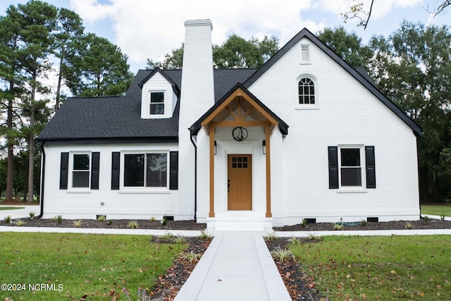 view of front of property with a front yard, a shingled roof, crawl space, brick siding, and a chimney