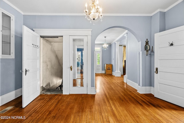 interior space with arched walkways, a notable chandelier, visible vents, ornamental molding, and wood finished floors