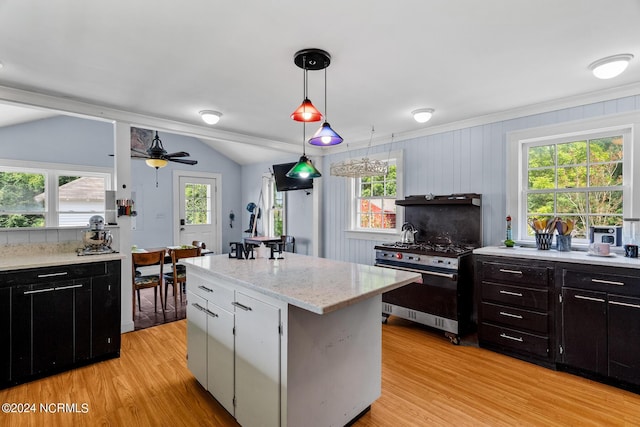 kitchen with a kitchen island, hanging light fixtures, vaulted ceiling, light wood-type flooring, and stainless steel range with gas cooktop