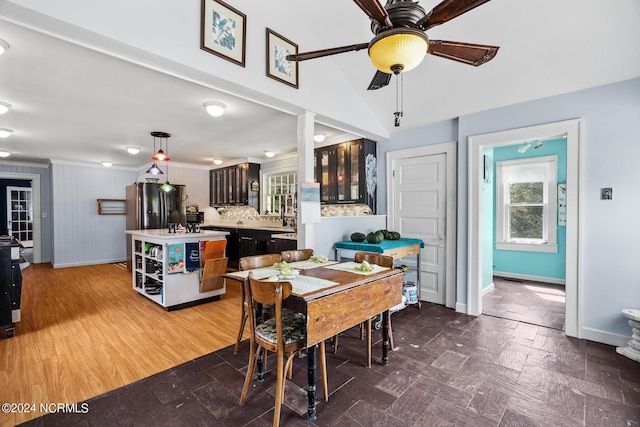 dining room with a ceiling fan, lofted ceiling, stone tile floors, and baseboards