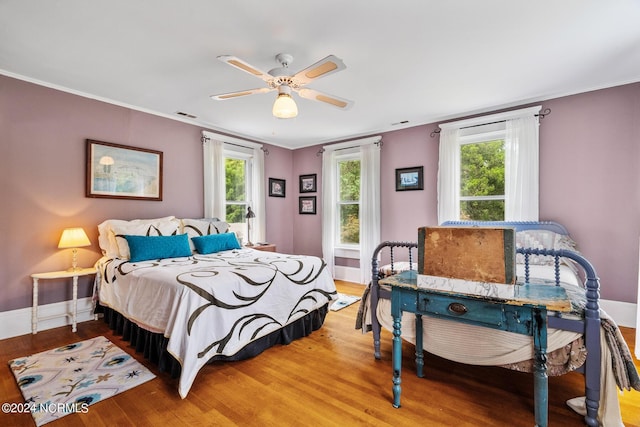 bedroom featuring ornamental molding, multiple windows, and wood finished floors