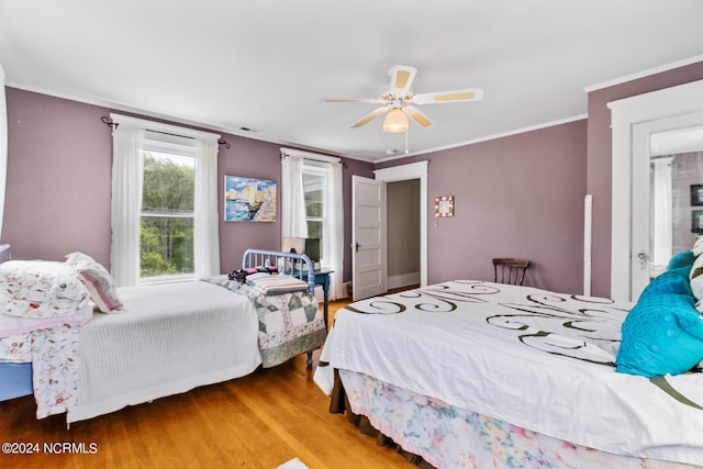 bedroom featuring a ceiling fan, visible vents, crown molding, and wood finished floors