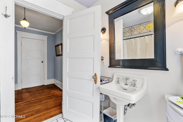 bathroom with baseboards, wood finished floors, and crown molding