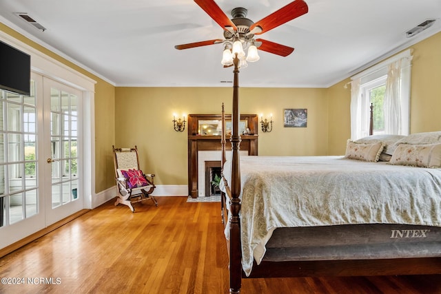 bedroom with access to outside, a brick fireplace, french doors, and wood finished floors