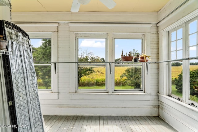 unfurnished sunroom featuring ceiling fan and plenty of natural light