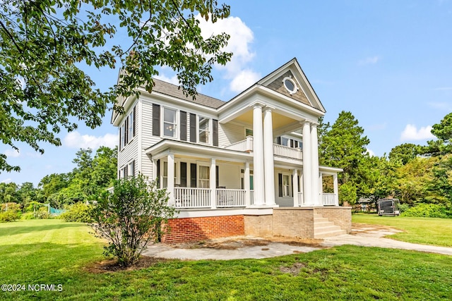 neoclassical home with a balcony, a front lawn, and a porch