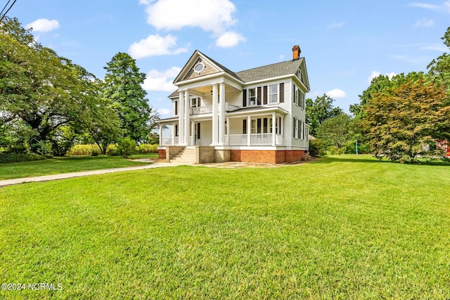 greek revival inspired property with covered porch, a chimney, and a front yard