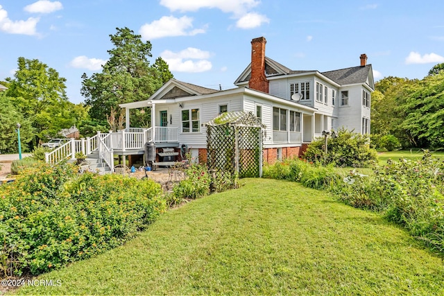 back of house featuring a chimney, stairway, a lawn, and a wooden deck