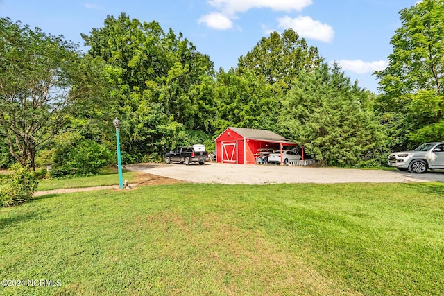 view of yard featuring driveway, a detached garage, and an outbuilding