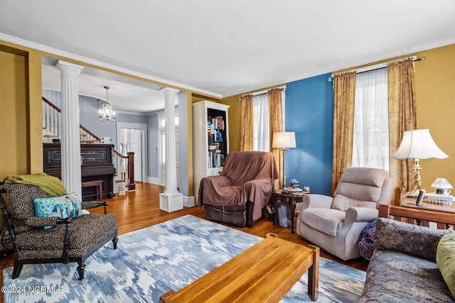 living room with decorative columns, stairs, ornamental molding, and wood finished floors