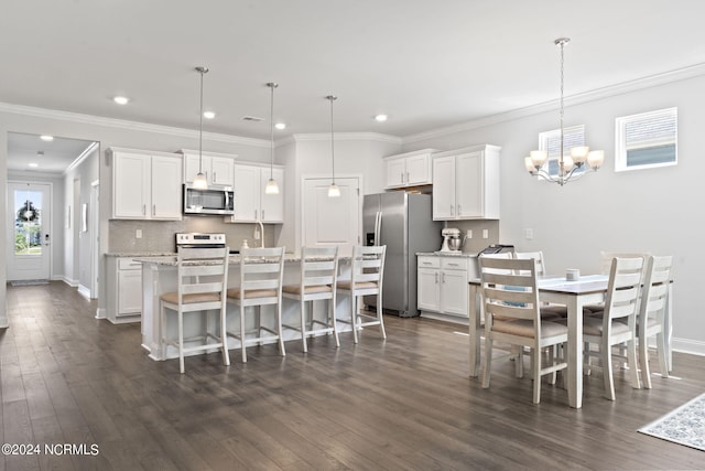 kitchen featuring appliances with stainless steel finishes, white cabinetry, dark wood-type flooring, and pendant lighting