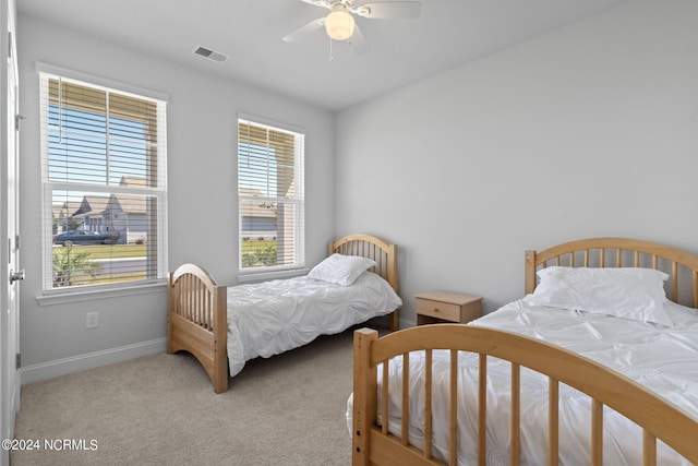 bedroom with multiple windows, ceiling fan, and light carpet