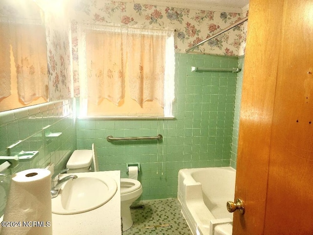 bathroom featuring toilet, a healthy amount of sunlight, wainscoting, a sink, and wallpapered walls