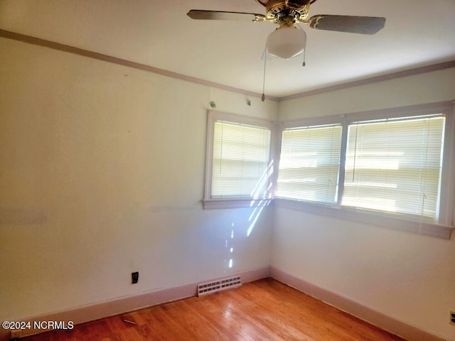 empty room with visible vents, light wood-style flooring, ornamental molding, ceiling fan, and baseboards