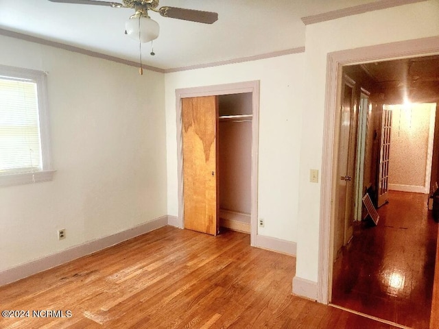 unfurnished bedroom with baseboards, a closet, ornamental molding, and wood finished floors