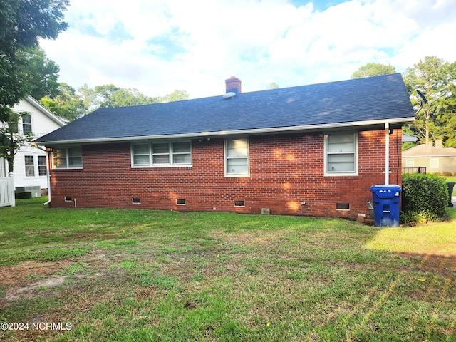 back of house featuring brick siding, a yard, a chimney, a shingled roof, and crawl space