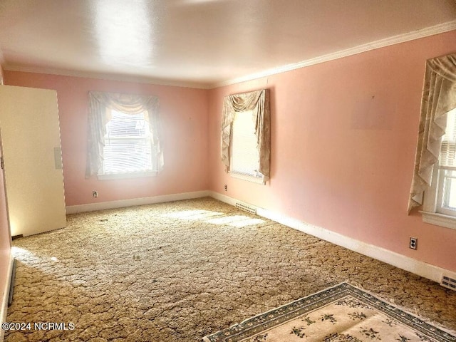 empty room featuring carpet floors, visible vents, baseboards, and crown molding