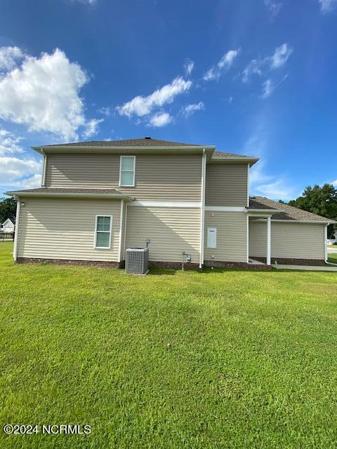 back of property with a lawn and central air condition unit