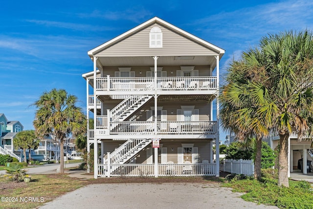 beach home featuring stairs, a porch, and fence