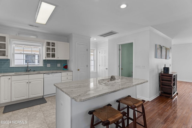 kitchen with dishwasher, a sink, visible vents, and a kitchen breakfast bar