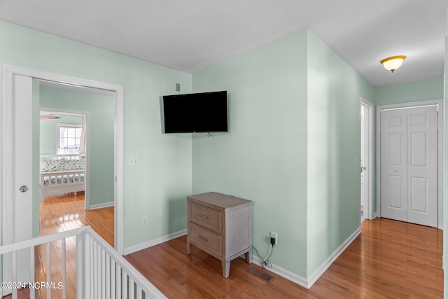 hall featuring visible vents, baseboards, and wood finished floors