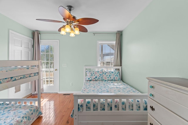 bedroom with access to outside, visible vents, ceiling fan, and wood finished floors