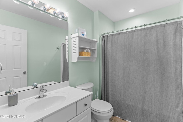 bathroom featuring curtained shower, vanity, and toilet