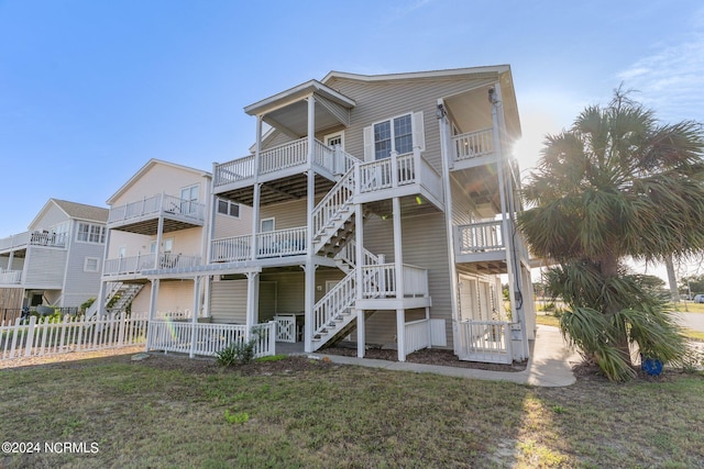 exterior space featuring fence, stairway, and a front lawn