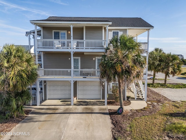 coastal home with driveway, stairway, and an attached garage