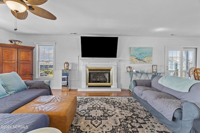 living area with a fireplace with raised hearth, crown molding, and wood finished floors