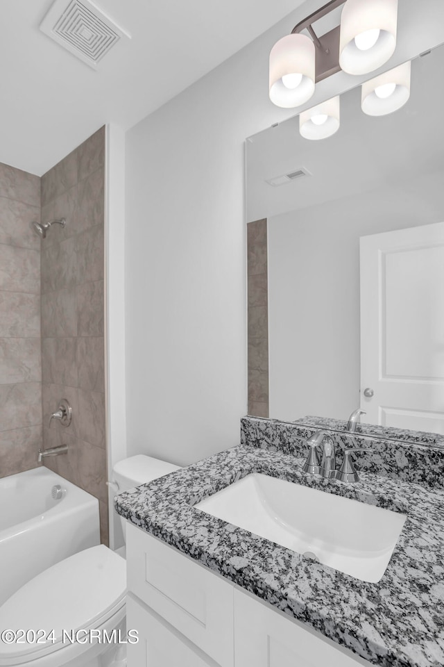 full bathroom featuring tiled shower / bath combo, vanity, and toilet